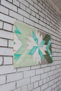 a white brick wall with a blue and green quilt hanging on it's side