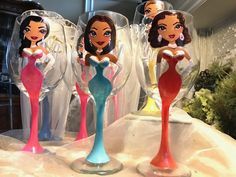 three disney princess wine glasses sitting on top of a table with other items in the background