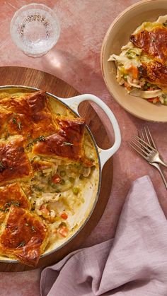 a casserole dish with meat and vegetables in it on a wooden platter