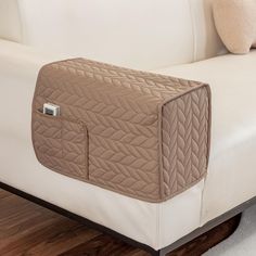 the back end of a white couch with a brown quilted cover on it's side