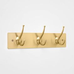 three hooks are attached to a coat hook on a white wall with gold colored handles