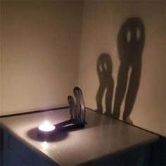 the shadow of two people standing next to each other in front of a lit candle