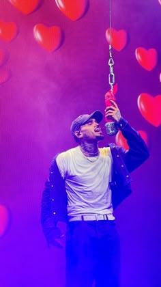 a man holding onto a red object with hearts on the wall in the back ground