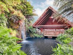 a house in the woods with a waterfall coming out of it's roof and surrounded by greenery