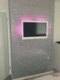 a tv mounted to the side of a wall in a room with glitter paint on it