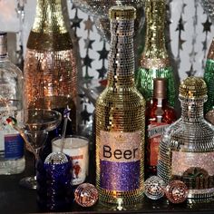 several different colored bottles and glasses on a table with silver sequins around them