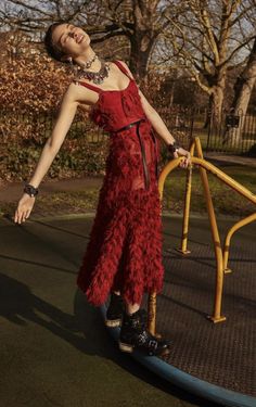 a woman in a red dress is standing on a skateboard