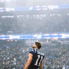 a man standing on top of a football field in front of a stadium filled with people