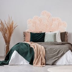 a bed with pillows and blankets on it next to a potted plant in the corner