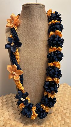 a blue and yellow flower necklace on a mannequin headpiece with gold ribbons