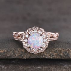 an opal and diamond ring on top of a rock