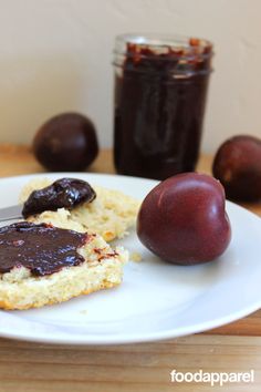 a piece of bread with chocolate spread on it and two plums in the background