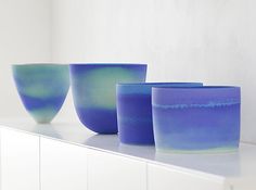 three blue glass bowls sitting on top of a white counter next to each other in front of a wall