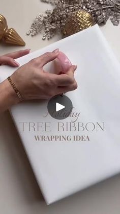 a person holding onto a white wrapping paper with the words tree ribbon wrapped in gold foil