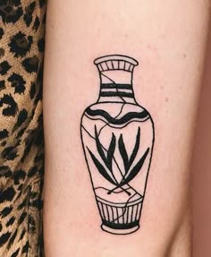 a black and white vase tattoo on the right arm with an arrow in it's center