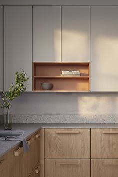 an empty kitchen with wooden cabinets and marble counter tops, along with a vase filled with flowers