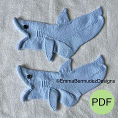 two knitted shark mitts sitting on top of a white cloth covered tablecloth