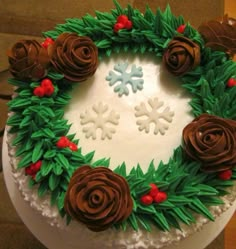 a cake decorated with frosting and flowers on top of a wooden table next to a wall