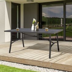 a table on a wooden deck in front of a building with glass doors and windows