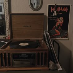 an old fashioned record player sitting on top of a table next to a wall with pictures