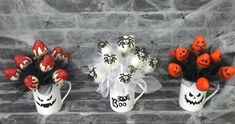 three vases with halloween decorations on them sitting next to each other in front of a stone wall