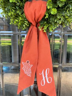 the monogrammed scarf is hanging on an iron gate with a wreath in front of it