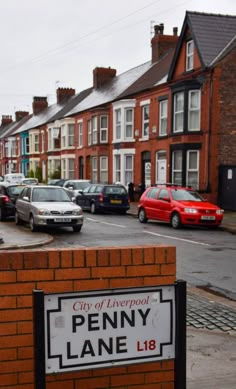 there is a sign that says penny lane in front of some cars parked on the street