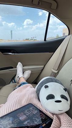 a person laying in the back seat of a car with a stuffed panda bear on their lap