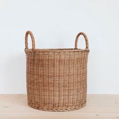 a wicker basket sitting on top of a wooden table next to a white wall