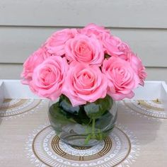 a clear vase filled with pink roses on top of a table