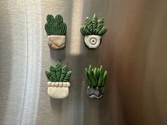 three small plants are placed on the side of a stainless steel refrigerator freezer door