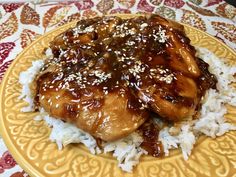 a yellow plate topped with rice and chicken covered in sauce on top of a table