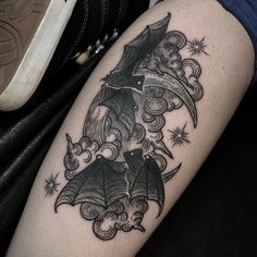 a black and white photo of a bat tattoo on the right thigh, with stars in the background