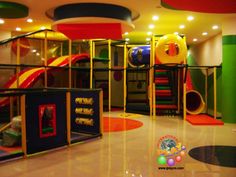 an indoor play area for children with slides and climbing walls in the center, surrounded by multicolored carpeting