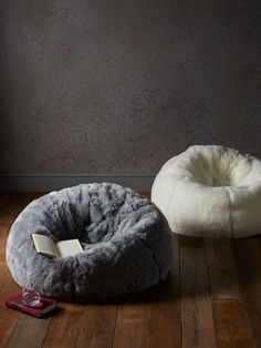 a dog bed with a book on the floor next to it in front of a gray wall