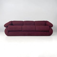 a red couch sitting on top of a white floor