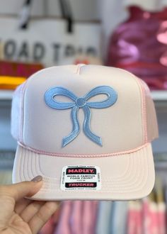 Get ready to turn heads with our Cutesie Pink & Blue Bow Trucker Hat! The trending bow pattern adds a touch of whimsy to this light pink trucker hat, accented with baby blue stitching. Made by Hats by Madley, this hat is perfect for anyone looking to add a playful and unique touch to their outfit. Cute Spring Trucker Hat With Curved Brim, Cute Spring Snapback Trucker Hat, Cute Snapback Trucker Hat For Spring, Cute Spring Snapback Hat, Playful White Trucker Hat For Spring, Cute Adjustable Snapback Hat For Spring, Cute Spring Baseball Cap, Playful Spring Trucker Hat With Curved Brim, Pink Snapback Hat For Spring