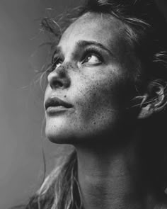 a black and white photo of a woman with freckled hair looking up at the sky