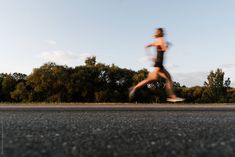 a person running on the road with trees in the background