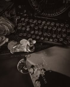 an old fashioned typewriter sitting on top of a table next to flowers and books