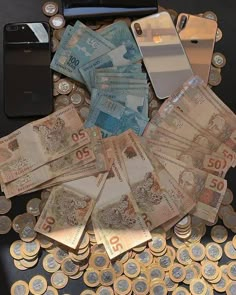 several different types of money sitting on top of a table next to a cell phone