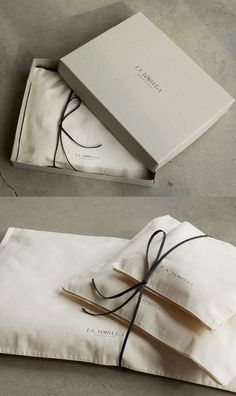 two boxes with ties tied to them sitting on top of a white cloth covered box