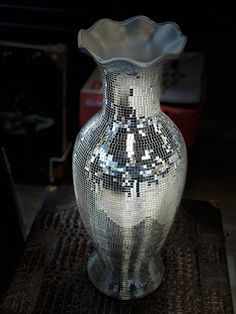 a silver vase sitting on top of a wooden table