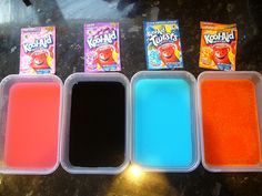 four different colored powders in plastic containers on a table next to two packets of gummy bears