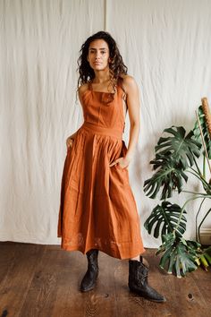 Rust Cara Pinny dress. Beautiful adjustable cross back with elastic waist band.  Pockets High grade lightweight cotton Suitable for size 6-12 Casual Backless Dress With Lace-up Back, Cotton Suspender Dress With Tie Straps For Day Out, Casual Cotton Sundress With Smocked Back, Backless Cotton Sundress With Tie Back, Cotton Sundress With Smocked Back For Casual Occasions, Cotton Sundress With Smocked Back For Casual Wear, Cotton Tie Back Backless Sundress, Cotton Backless Sundress With Tie Back, Cotton Sundress With Square Neck Suspender