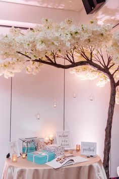 the table is set up for a wedding with white flowers on it and candles in front