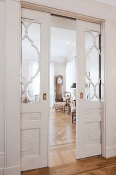 an open door leading to a living room with wood floors and white walls in the background