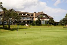 people playing golf in front of a large house