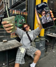 a woman sitting on the ground holding up a cell phone