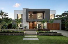 a modern house with grass and trees in the front yard